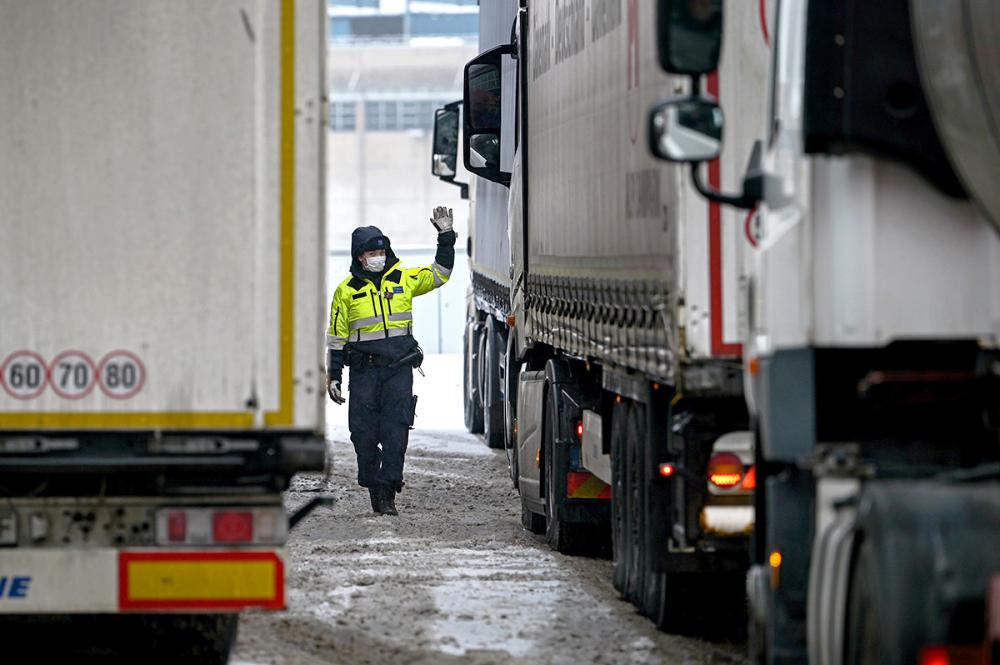 Tullin työntekijä ohjaa kuorma-autoja, maassa lunta.