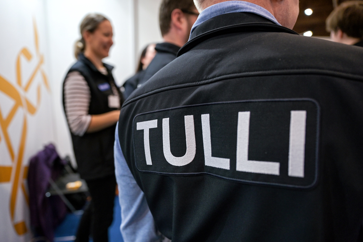 I förgrunden finns en person med texten Tulli på ryggen. I bakgrunden syns andra personer.